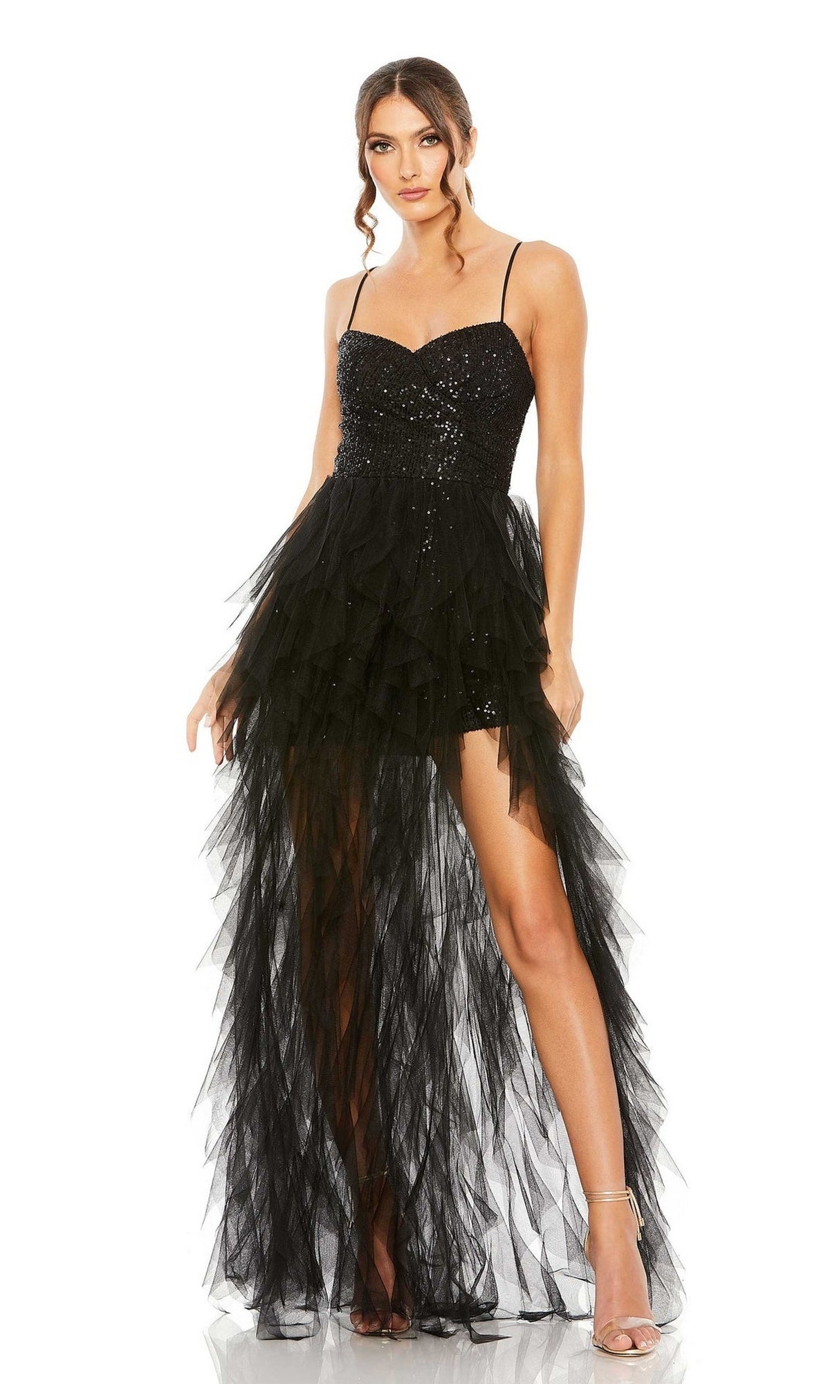 A woman confidently poses in the Mac Duggal 27119 Overskirt Mini Sequin Prom Dress, featuring thin straps, a sleeveless black sequin bodice, and a sheer layered high-low skirt.